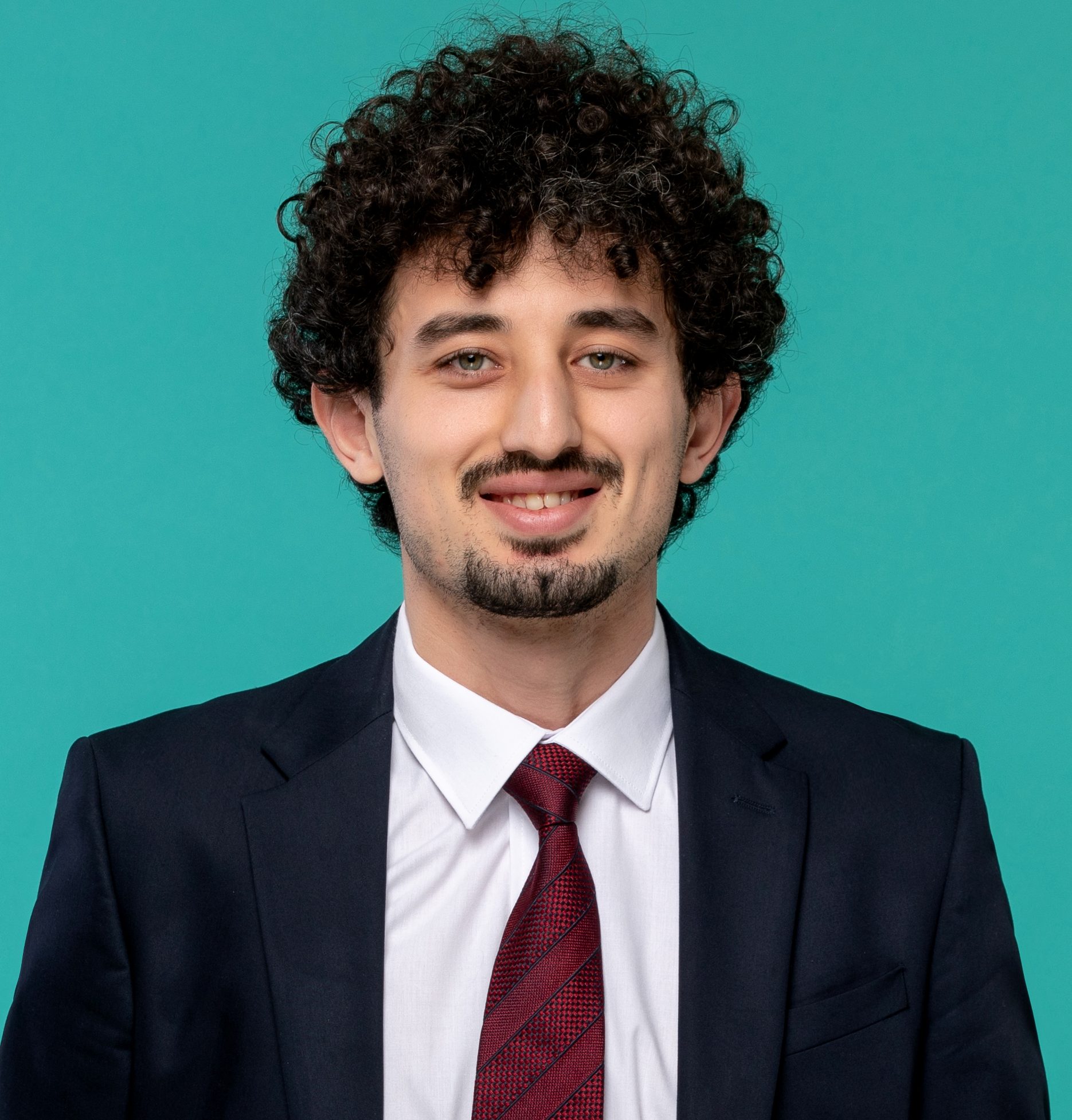 Paradise Medical Maui, Professional man with curly hair in suit and tie, smiling at the camera.