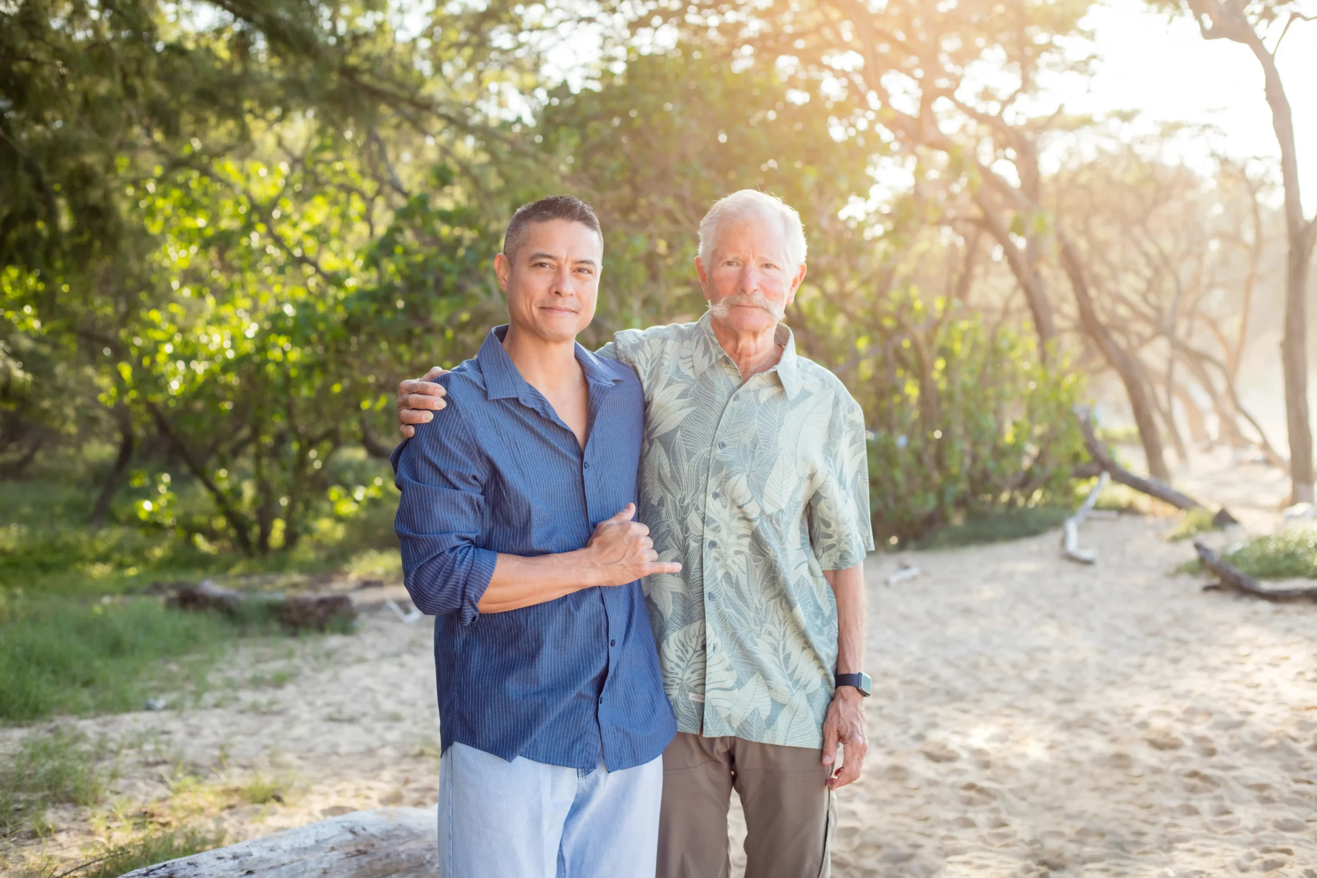 Paradise Medical Maui, Two men pose on a beach, one with arm around the other.
