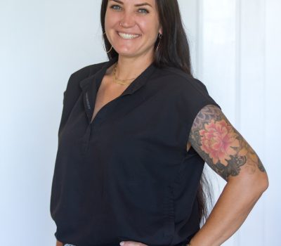 Paradise Medical Maui, Smiling healthcare worker in black scrubs with floral tattoo on arm.