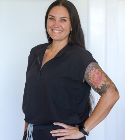 Paradise Medical Maui, Smiling healthcare worker in black scrubs with floral tattoo on arm.