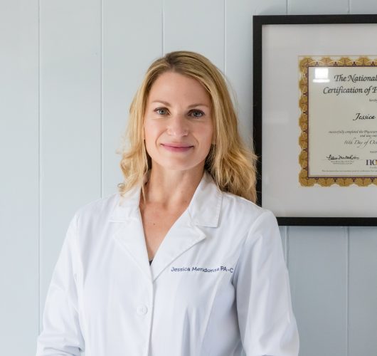 Paradise Medical Maui, Jessica Mendonsa, PA-C, in lab coat with medical certification in background. Healthcare professional.