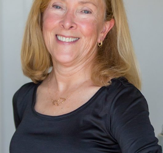 Paradise Medical Maui, Smiling mature woman with blonde hair wearing a black top and gold necklace.